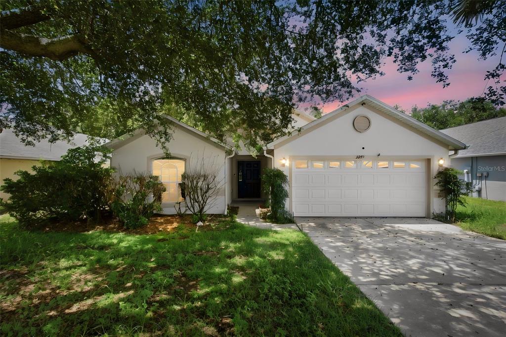 A single-story house with a white stucco exterior, a two-car garage, and a front lawn — 2255 MERRY ROAD, TAVARES, FL