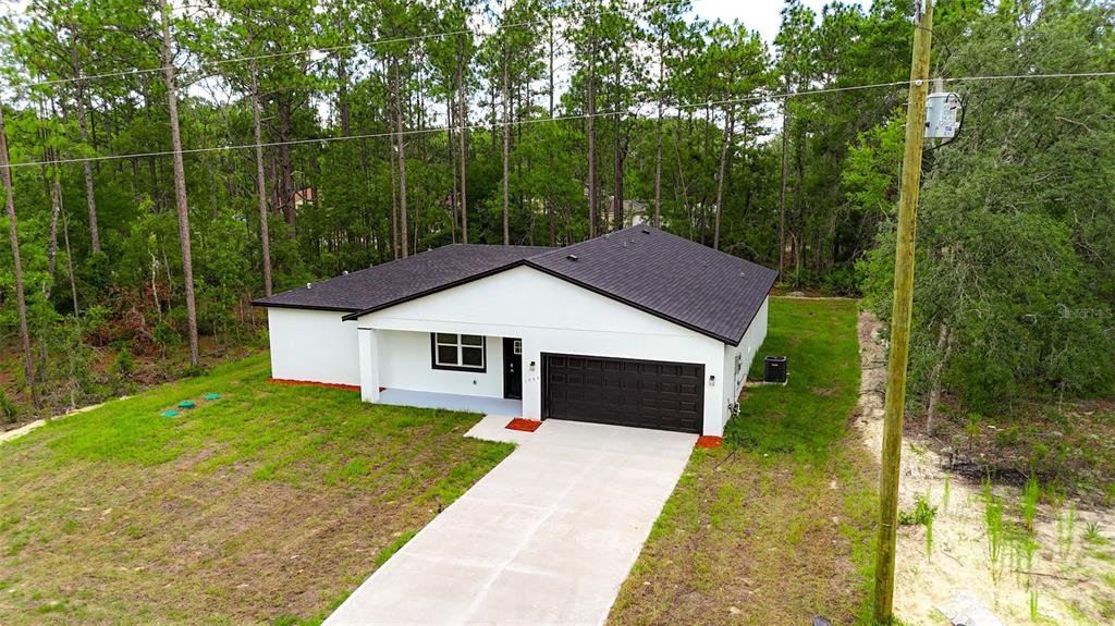 An aerial view of a white single-story house with a dark roof and garage — 1902 W ADELIA PLACE, CITRUS SPRINGS, FL