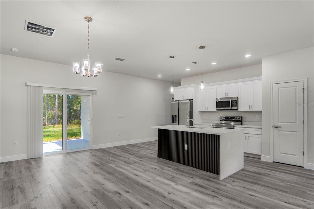 A kitchen with white cabinets, a slatted island, and gray wood-look flooring — 1902 W ADELIA PLACE, CITRUS SPRINGS, FL