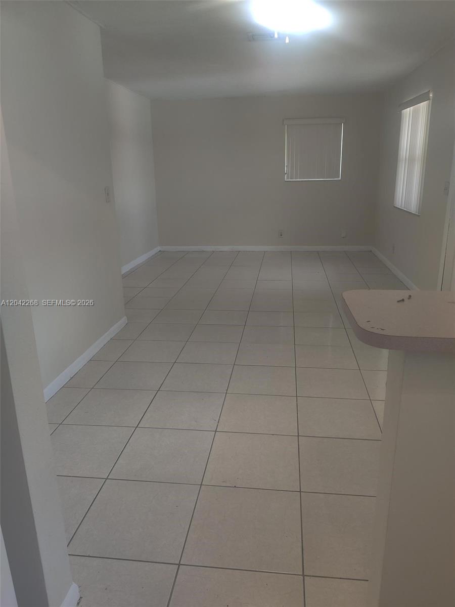 An empty room features light-colored floor tiles, white walls, and two windows with blinds — 844 SW 10th St # 3, Hallandale Beach FL 33009, HALLANDALE BEACH, FL