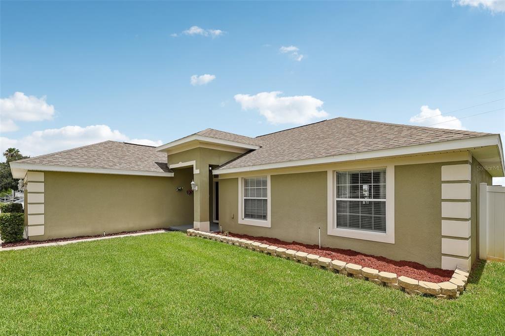 A single-story house with tan stucco walls, a shingled roof, and a front lawn — 1980 BIG BUCK DRIVE, ST CLOUD, FL