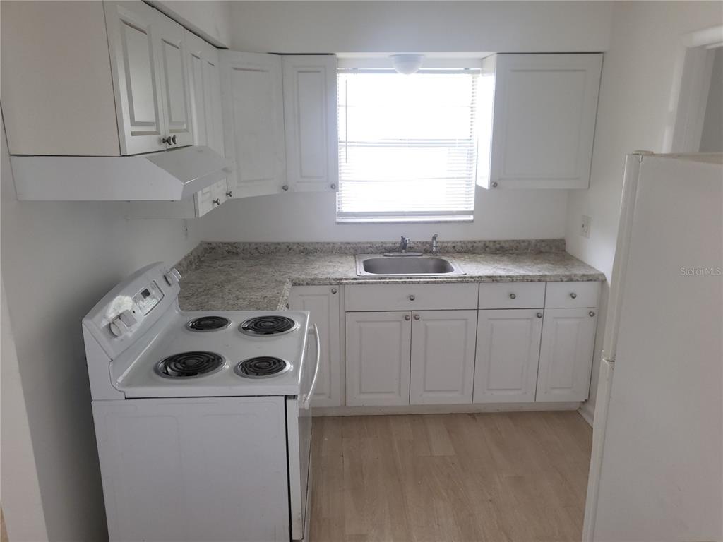 A kitchen features white cabinets, a white electric stove, a sink, and light-colored countertops — 2185 NW 3RD STREET, OKEECHOBEE, FL