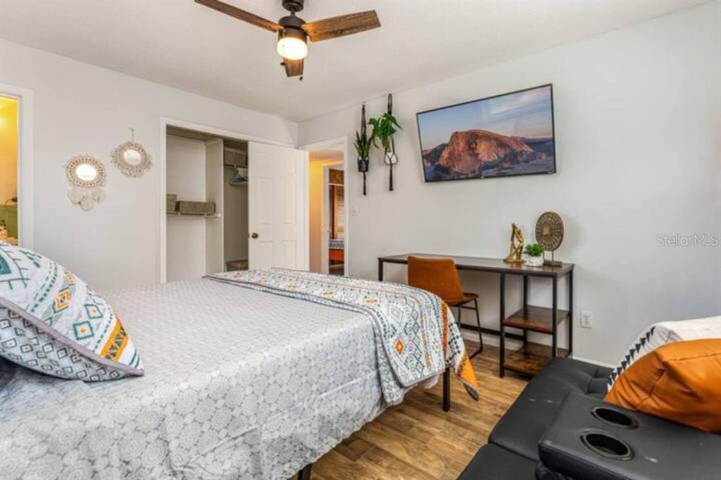 A bedroom features a bed, a desk with a chair, a television, and wood-look flooring — 4326 BLONIGEN AVE, ORLANDO, FL