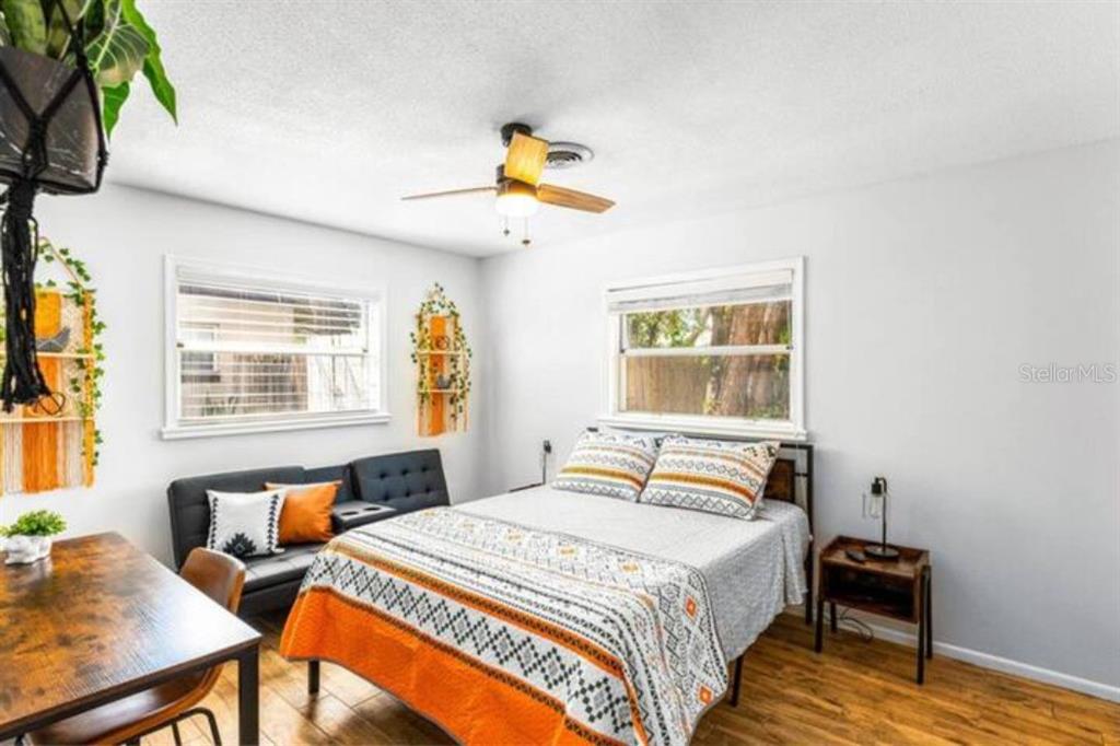 A bedroom features a bed with patterned bedding, a small sofa, and a wooden desk — 4326 BLONIGEN AVE, ORLANDO, FL