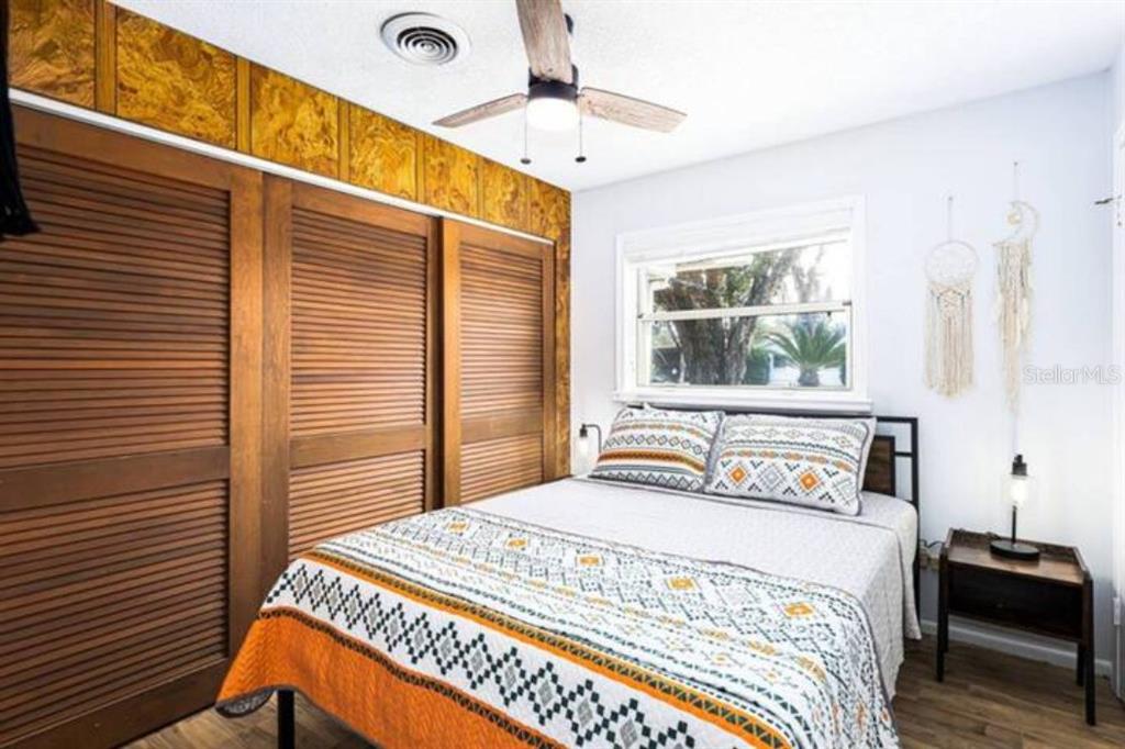 A bedroom features a bed with patterned bedding, wood louvered closet doors, and a ceiling fan — 4326 BLONIGEN AVE, ORLANDO, FL