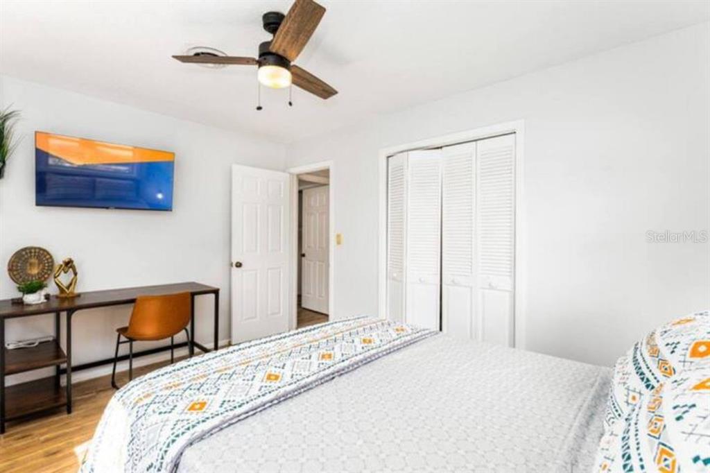 A bedroom features a bed, a desk with a chair, a ceiling fan, and closet doors — 4326 BLONIGEN AVE, ORLANDO, FL