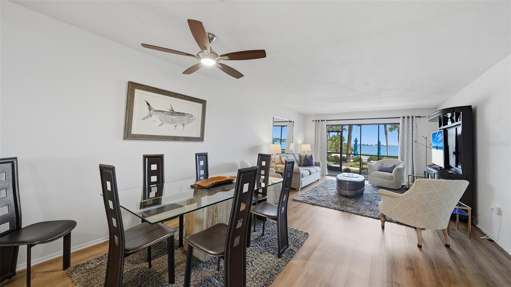 A living room features a gray sofa, two armchairs, a television console, and a water view — 1602 STICKNEY POINT ROAD UNIT 2-104, SARASOTA, FL