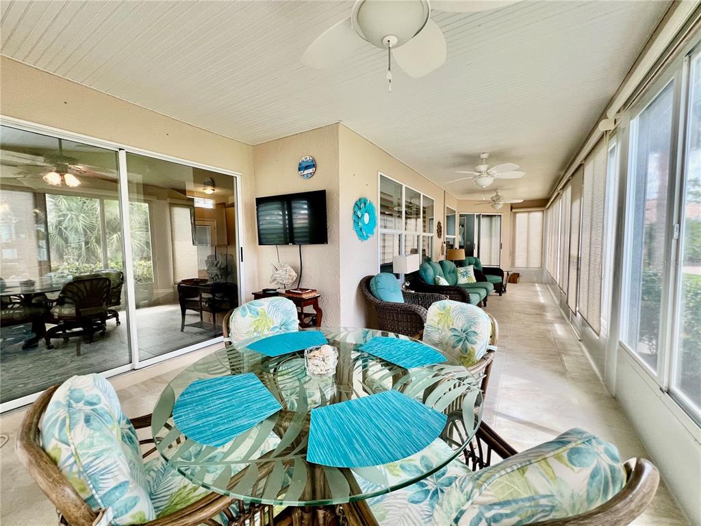 A sunroom features a glass-topped dining table, wicker furniture, ceiling fans, and large sliding windows — 1010 ISLAMORADA BOULEVARD, PUNTA GORDA, FL
