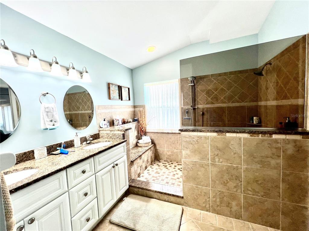 A bathroom features a double vanity with granite countertops and a large walk-in tiled shower — 1010 ISLAMORADA BOULEVARD, PUNTA GORDA, FL