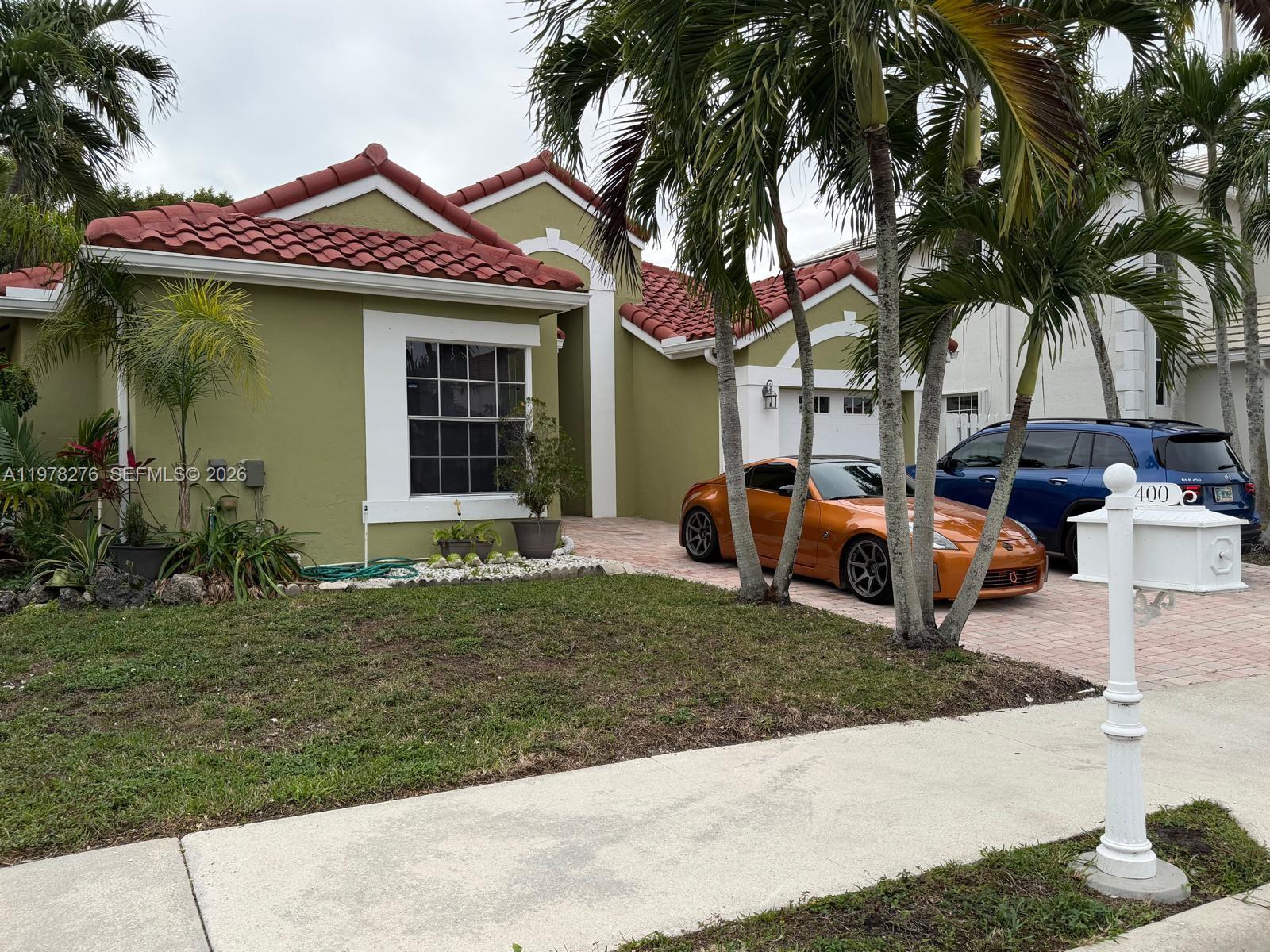 A single-story house with a green exterior, red tile roof, and two cars parked outside — 400 Somerset Way, Weston FL 33326, WESTON, FL