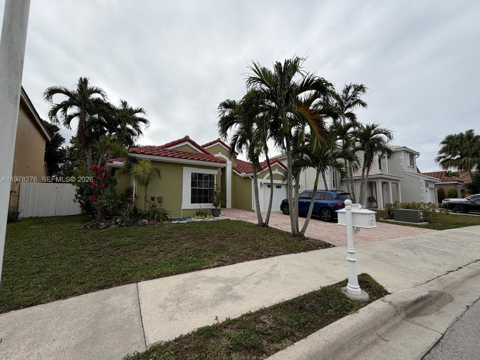 A single-story house with green stucco walls, a red tile roof, and palm trees — 400 Somerset Way, Weston FL 33326, WESTON, FL