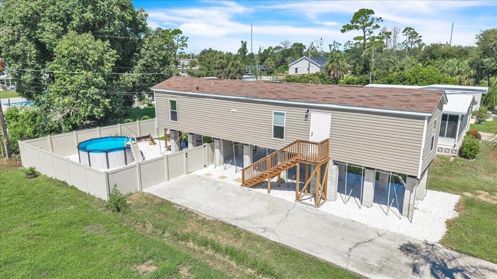 An elevated mobile home with a wooden staircase, concrete driveway, and a fenced-in swimming pool — 3702 DUNREATH ROAD, PORT CHARLOTTE, FL