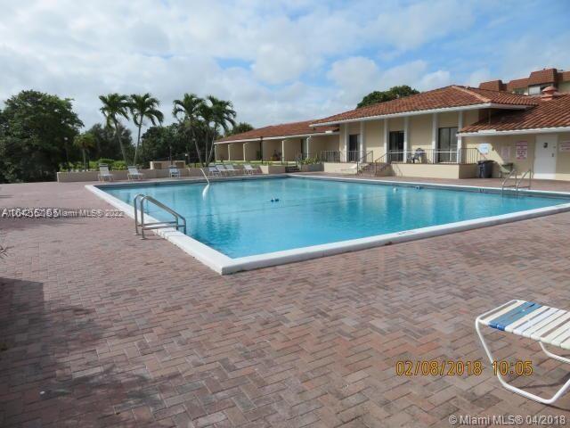 A rectangular swimming pool sits on a brick patio in front of a low-rise building — 4170 Inverrary Dr # 111, Lauderhill FL 33319, LAUDERHILL, FL