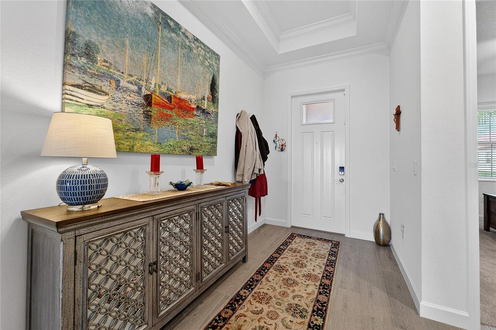 A bright entryway features a patterned console table, a large landscape painting, and a runner rug — 17216 SCUBA CREST STREET, WIMAUMA, FL