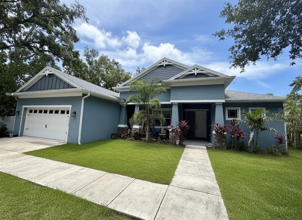 A blue single-story house with a white garage door, stone accents, and a concrete walkway — 11560 110TH AVENUE, LARGO, FL