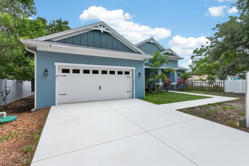 A blue house with a white garage door and a concrete driveway under a sky — 11560 110TH AVENUE, LARGO, FL