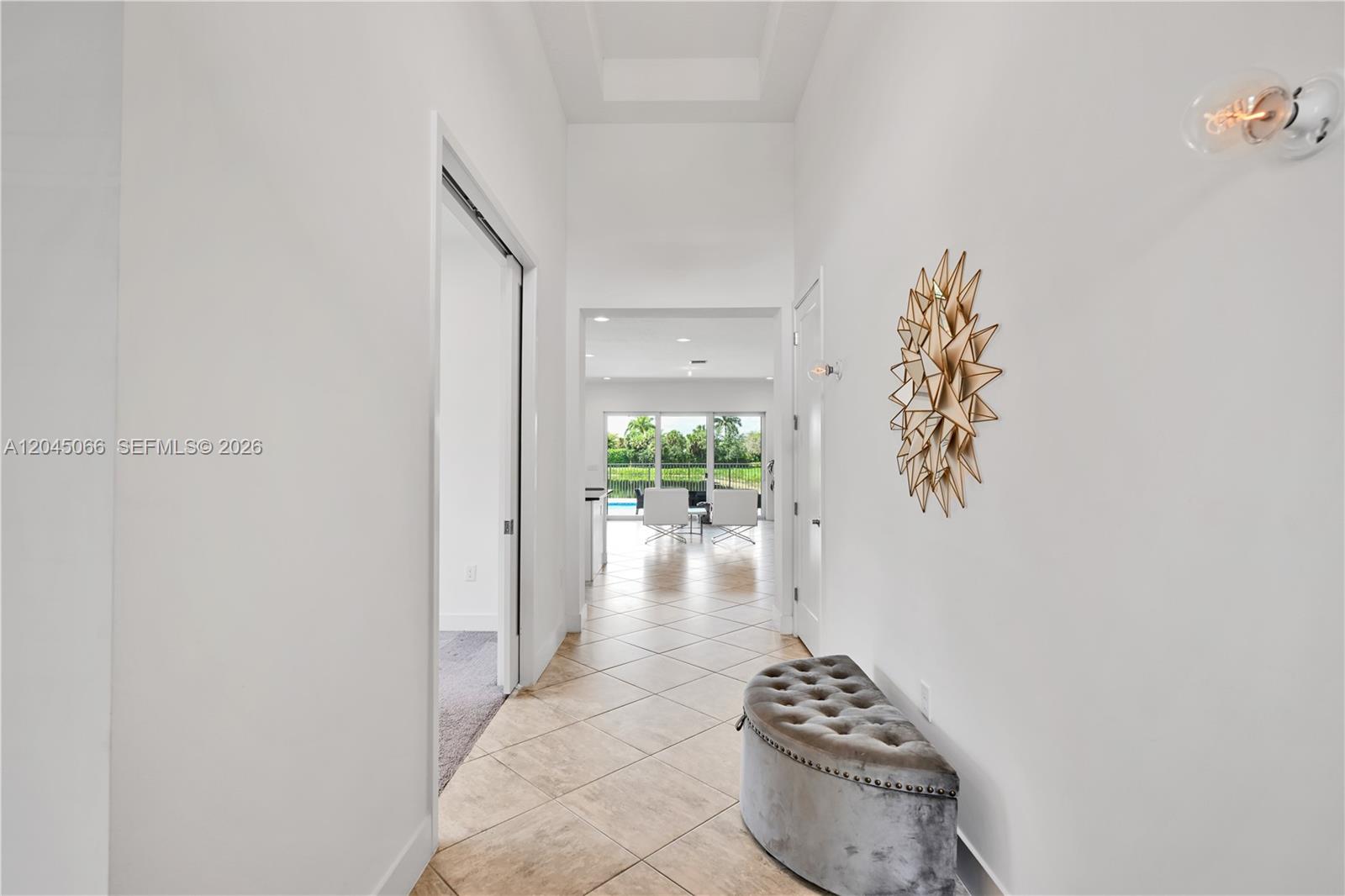 A hallway with tiled floors leads to a bright living area with a pool view — 9706 Celtic Sea Ln, Delray Beach FL 33446, DELRAY BEACH, FL