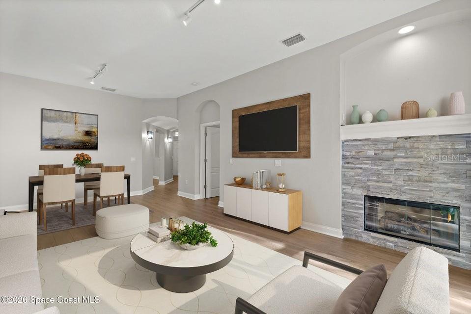 A living room features a stone fireplace, a wall-mounted television, and an adjacent dining area — 1741 KINSALE COURT, MELBOURNE, FL