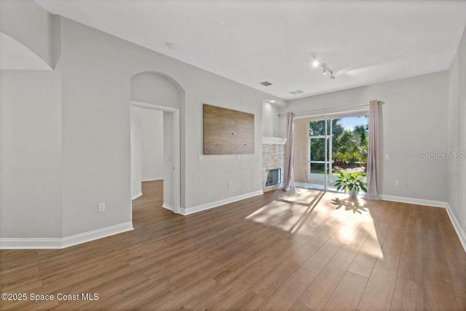A living room features light gray walls, wood-look flooring, a fireplace, and sliding glass doors — 1741 KINSALE COURT, MELBOURNE, FL