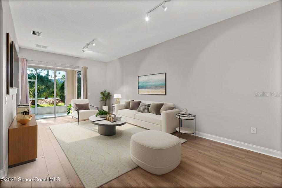 A bright living room features a sofa, coffee table, area rug, and sliding glass doors — 1741 KINSALE COURT, MELBOURNE, FL