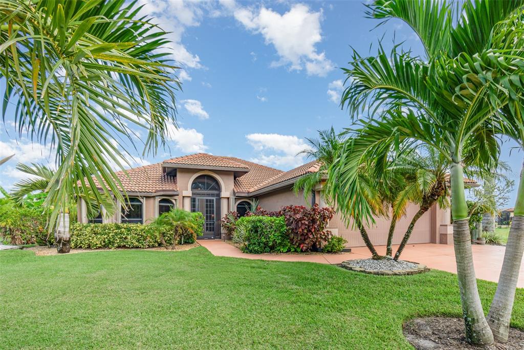 A single-story house with a tiled roof, arched entryway, and palm trees in the yard — 2239 OLD BURNT STORE ROAD N, CAPE CORAL, FL
