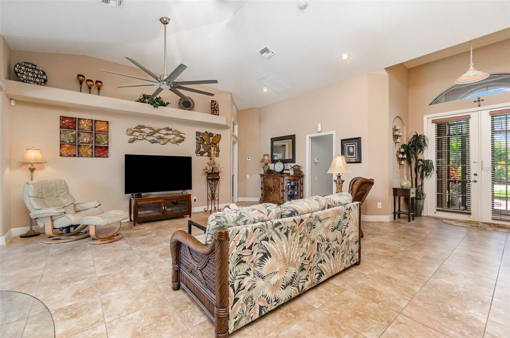 A living room features tile flooring, a vaulted ceiling with a fan, and a television console — 2239 OLD BURNT STORE ROAD N, CAPE CORAL, FL