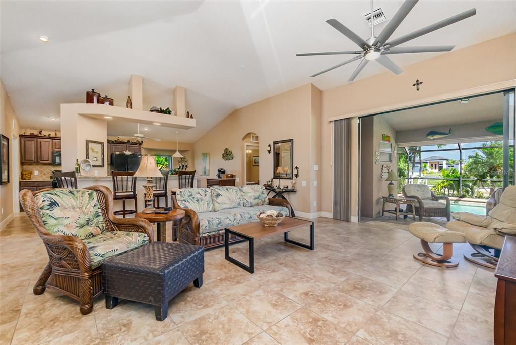 A living room with tile floors, a vaulted ceiling, and sliding doors opening to a pool — 2239 OLD BURNT STORE ROAD N, CAPE CORAL, FL