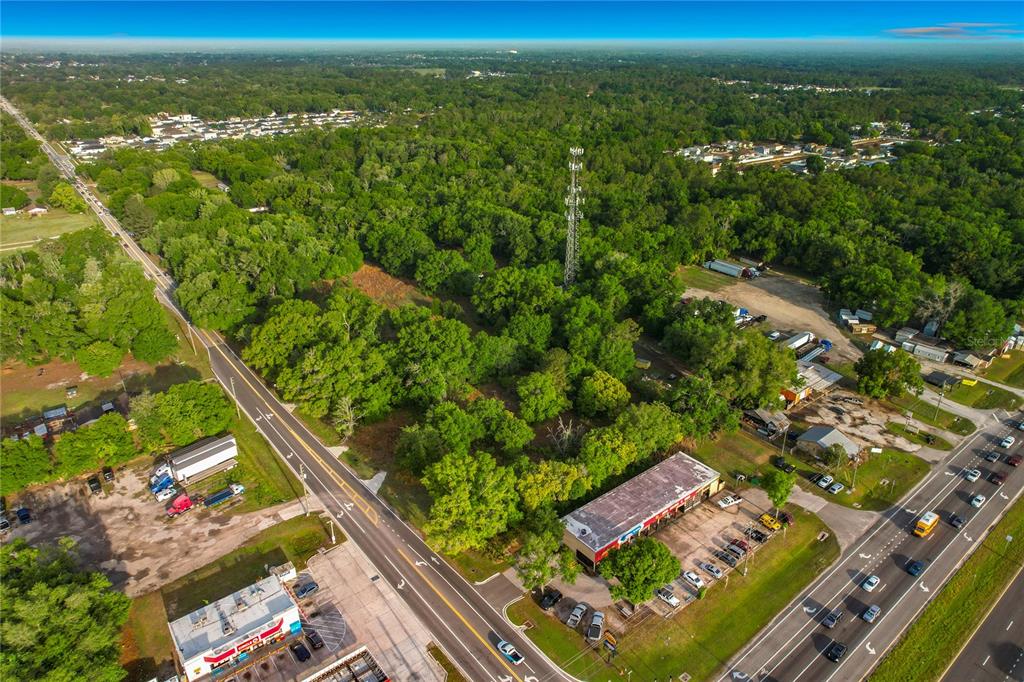 An aerial view shows a wooded lot situated between two roads with a cell tower — 1301, 1225, 1215 DUFF RD, LAKELAND, FL
