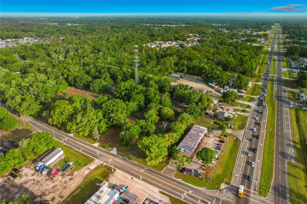 An aerial view shows a wooded lot with a cell tower near a highway — 1301, 1225, 1215 DUFF RD, LAKELAND, FL
