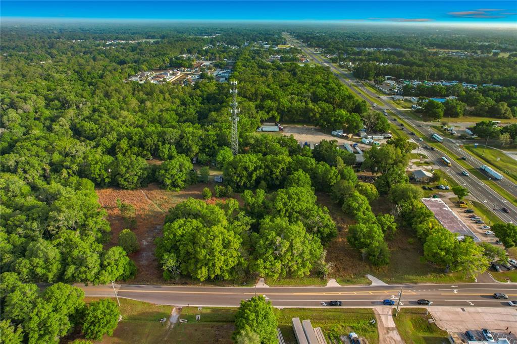 An aerial view shows a wooded lot with a cell tower near a highway — 1301, 1225, 1215 DUFF RD, LAKELAND, FL