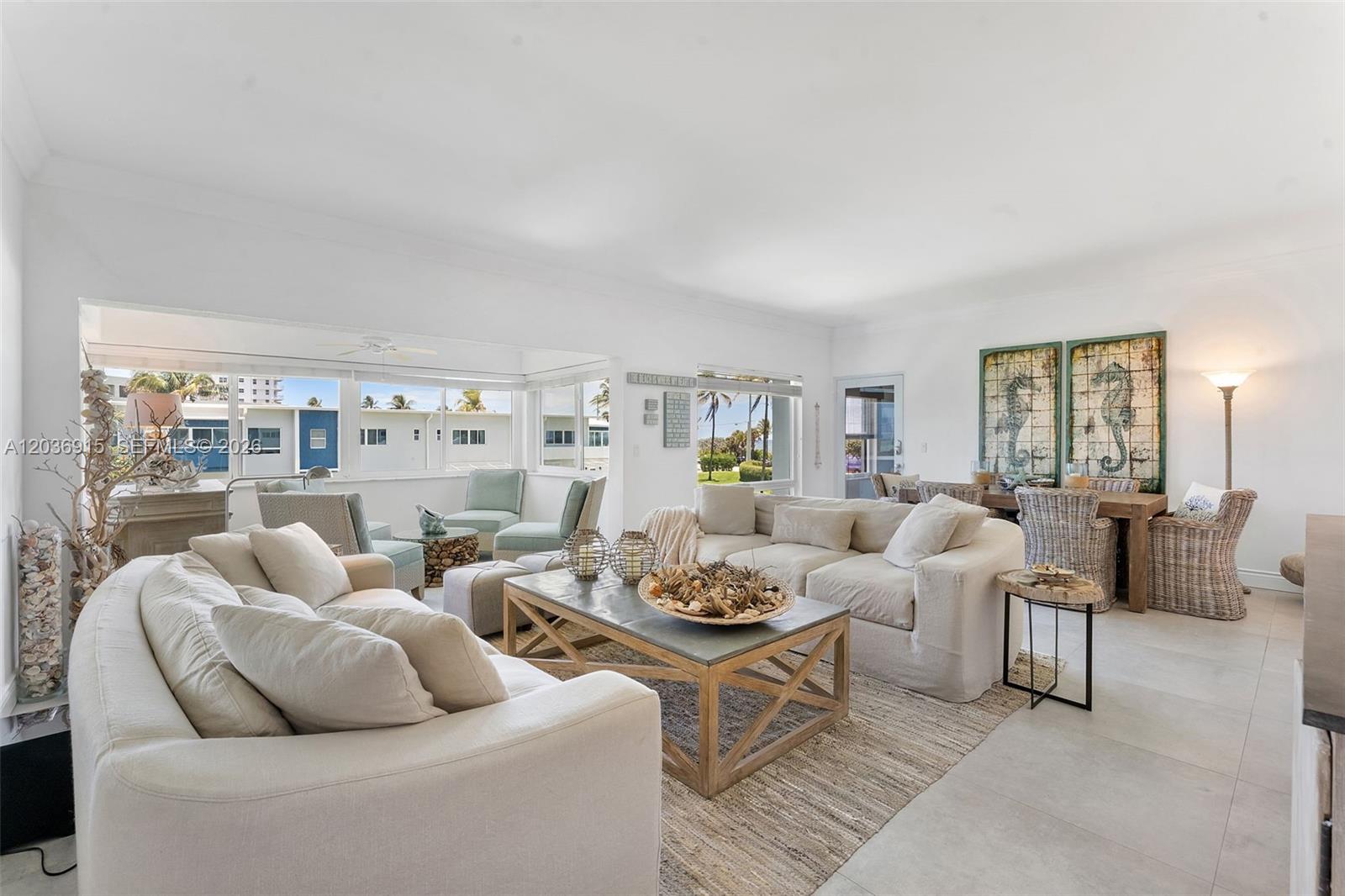 A bright living room features white sofas, a wooden coffee table, and a dining area — 120 N Ocean Blvd # 6, Delray Beach FL 33483, DELRAY BEACH, FL