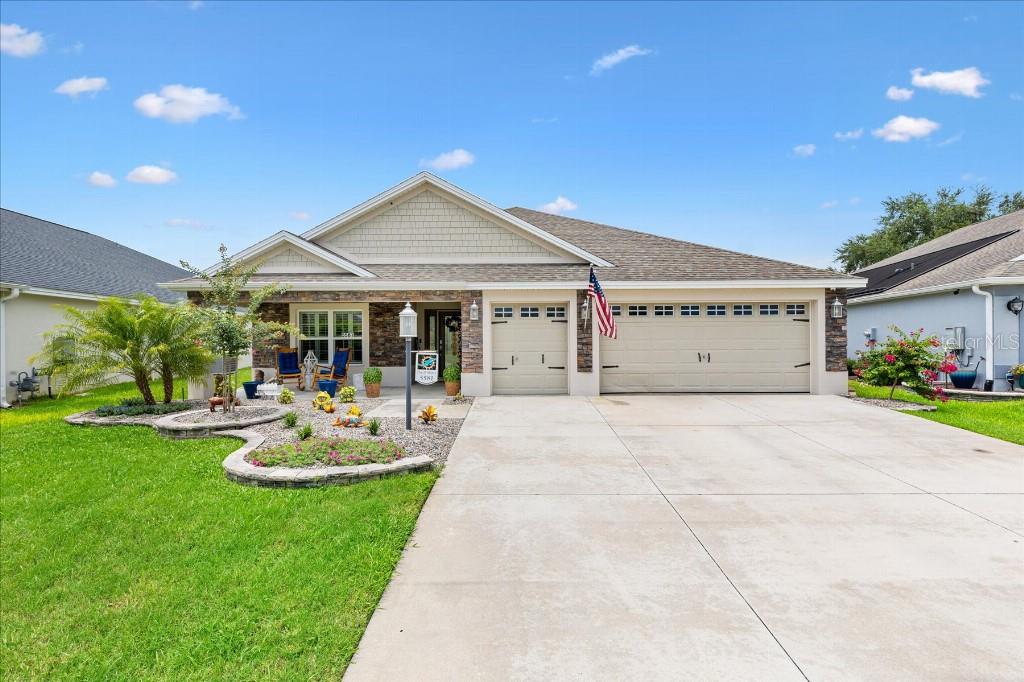 A single-story house with a stone facade, a three-car garage, and a landscaped front yard — 5581 PASSION FLOWER WAY, THE VILLAGES, FL