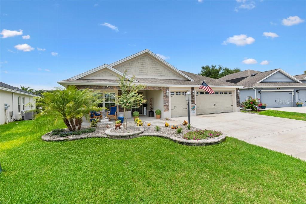 A single-story house with a stone facade, a two-car garage, and a landscaped front yard — 5581 PASSION FLOWER WAY, THE VILLAGES, FL