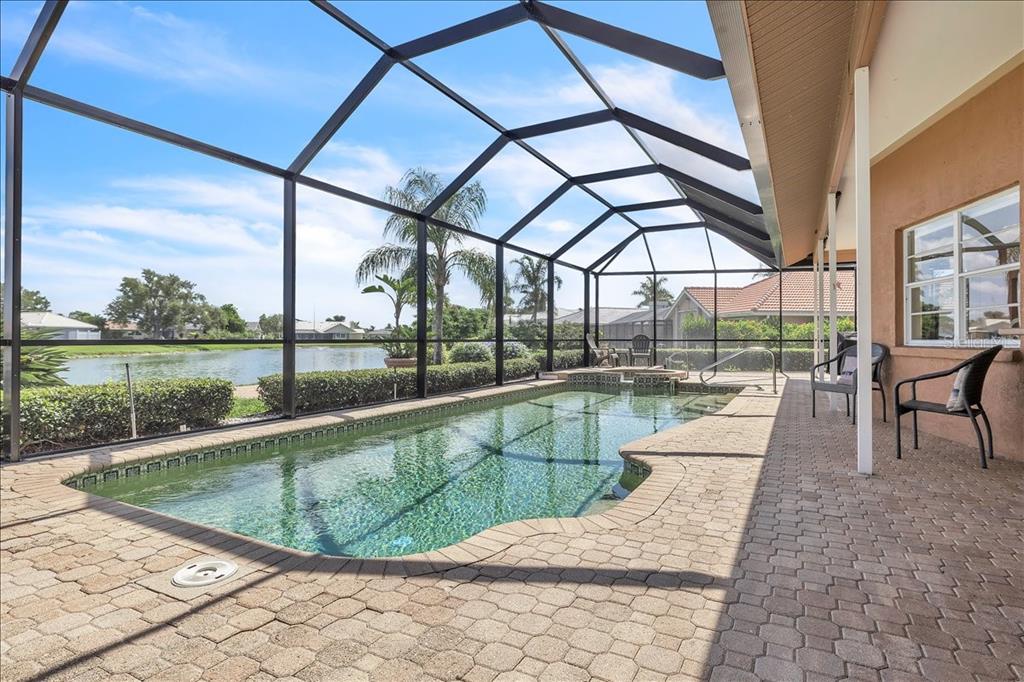 A screened-in swimming pool with a brick paver deck overlooks a lake — 373 EDEN DRIVE, ENGLEWOOD, FL