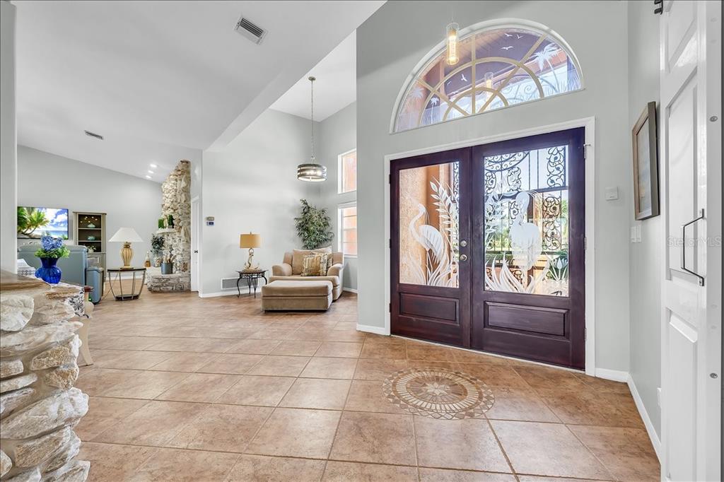 A bright foyer features tile flooring, a stone accent wall, and double doors with glass inserts — 373 EDEN DRIVE, ENGLEWOOD, FL