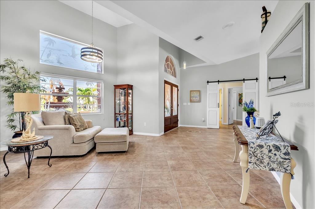 A spacious living area features tile flooring, high ceilings, a large window, and double doors — 373 EDEN DRIVE, ENGLEWOOD, FL