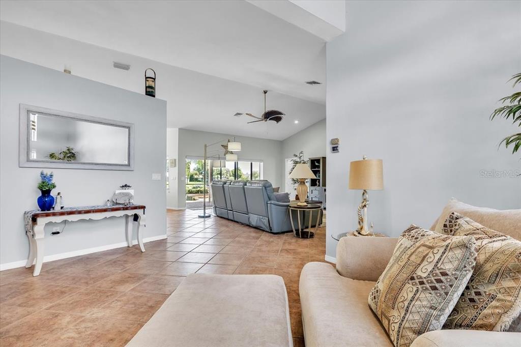 A living room features tile flooring, a vaulted ceiling, and a view toward the patio — 373 EDEN DRIVE, ENGLEWOOD, FL