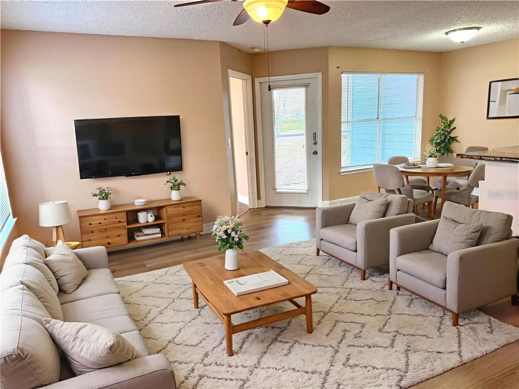 A living room features a beige sofa, two armchairs, a wooden coffee table, and a television — 731 SUGAR BAY WAY UNIT 103, LAKE MARY, FL