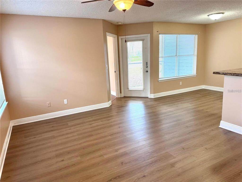 An empty room features light-colored walls, wood-look flooring, a ceiling fan, and a glass-paneled door — 731 SUGAR BAY WAY UNIT 103, LAKE MARY, FL