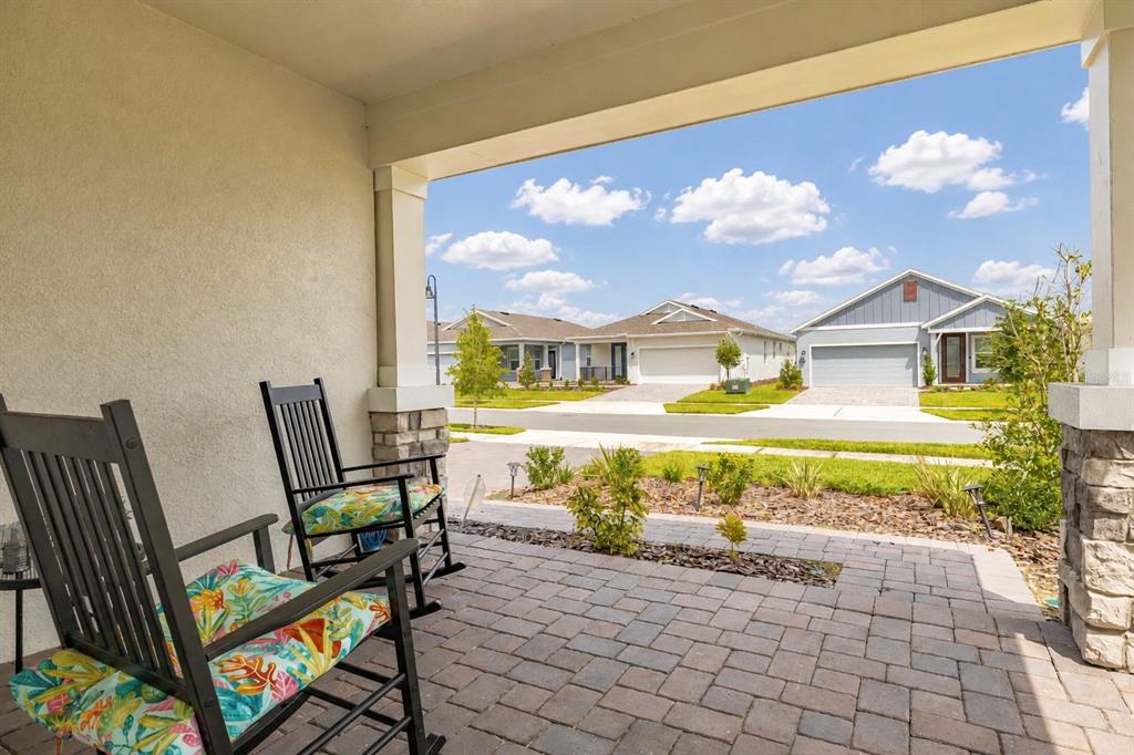 A covered front porch with two rocking chairs overlooks a suburban street and neighboring houses — 4536 OCHOS RIOS PLACE, KISSIMMEE, FL