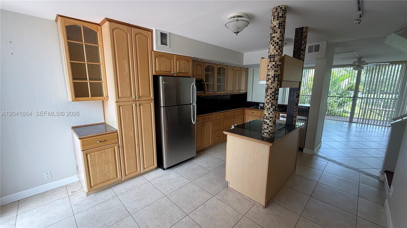 A kitchen features light wood cabinets, stainless steel appliances, a tiled island, and tile flooring — 2921 SW 87th Ave # 511, Davie FL 33328, DAVIE, FL