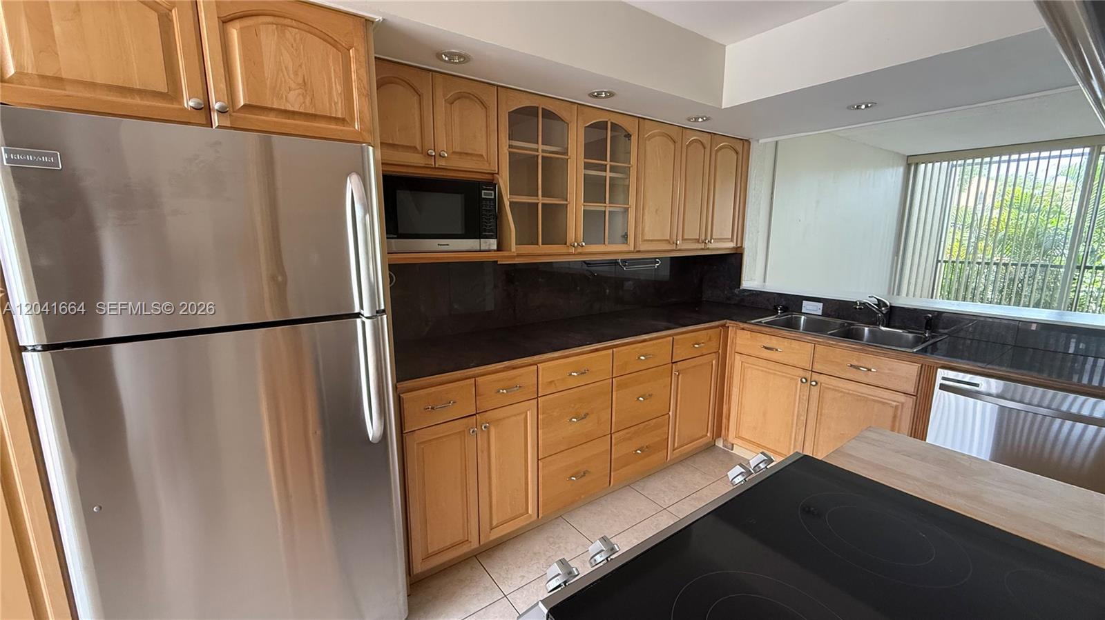 A kitchen features light wood cabinets, stainless steel appliances, and dark countertops — 2921 SW 87th Ave # 511, Davie FL 33328, DAVIE, FL