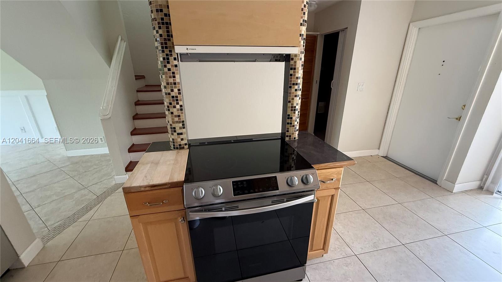 A kitchen features a slide-in electric range with a tiled backsplash and wooden cabinets — 2921 SW 87th Ave # 511, Davie FL 33328, DAVIE, FL