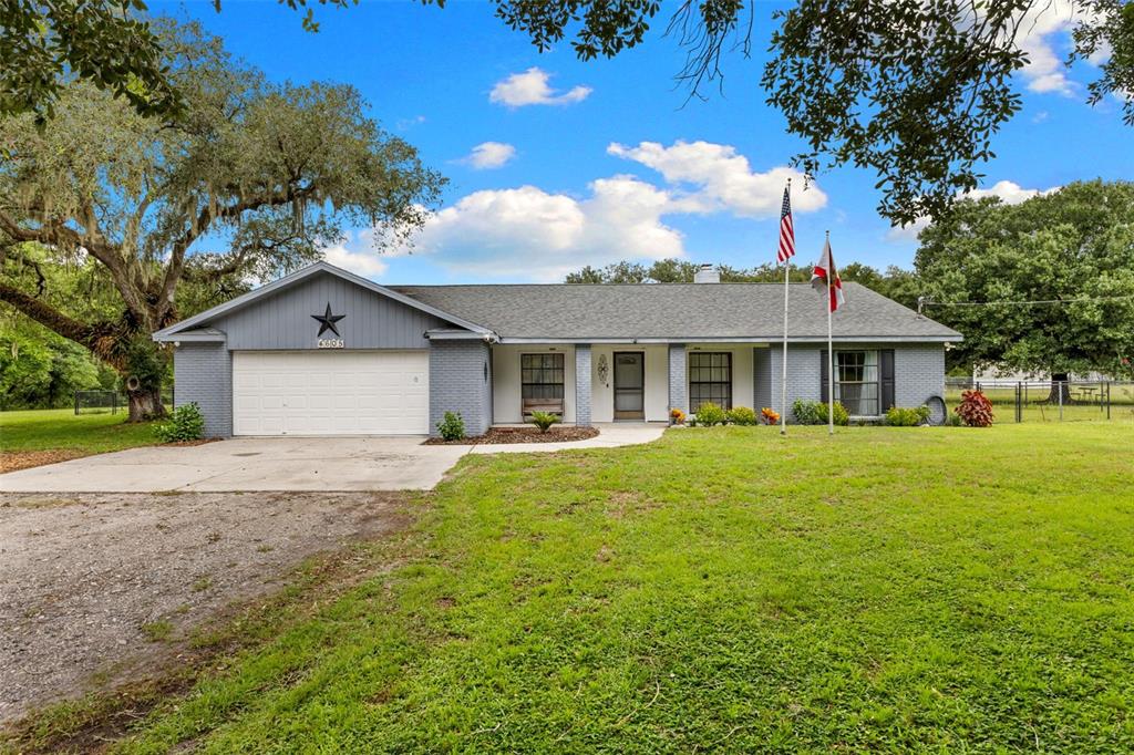 A single-story gray brick house with a two-car garage and a large front lawn — 4605 POST HOUSE DRIVE, PLANT CITY, FL