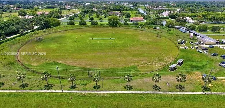 An aerial view shows a large circular cricket field surrounded by trees and parking areas — n/a El Paraiso Pl, Delray Beach FL 33446, DELRAY BEACH, FL