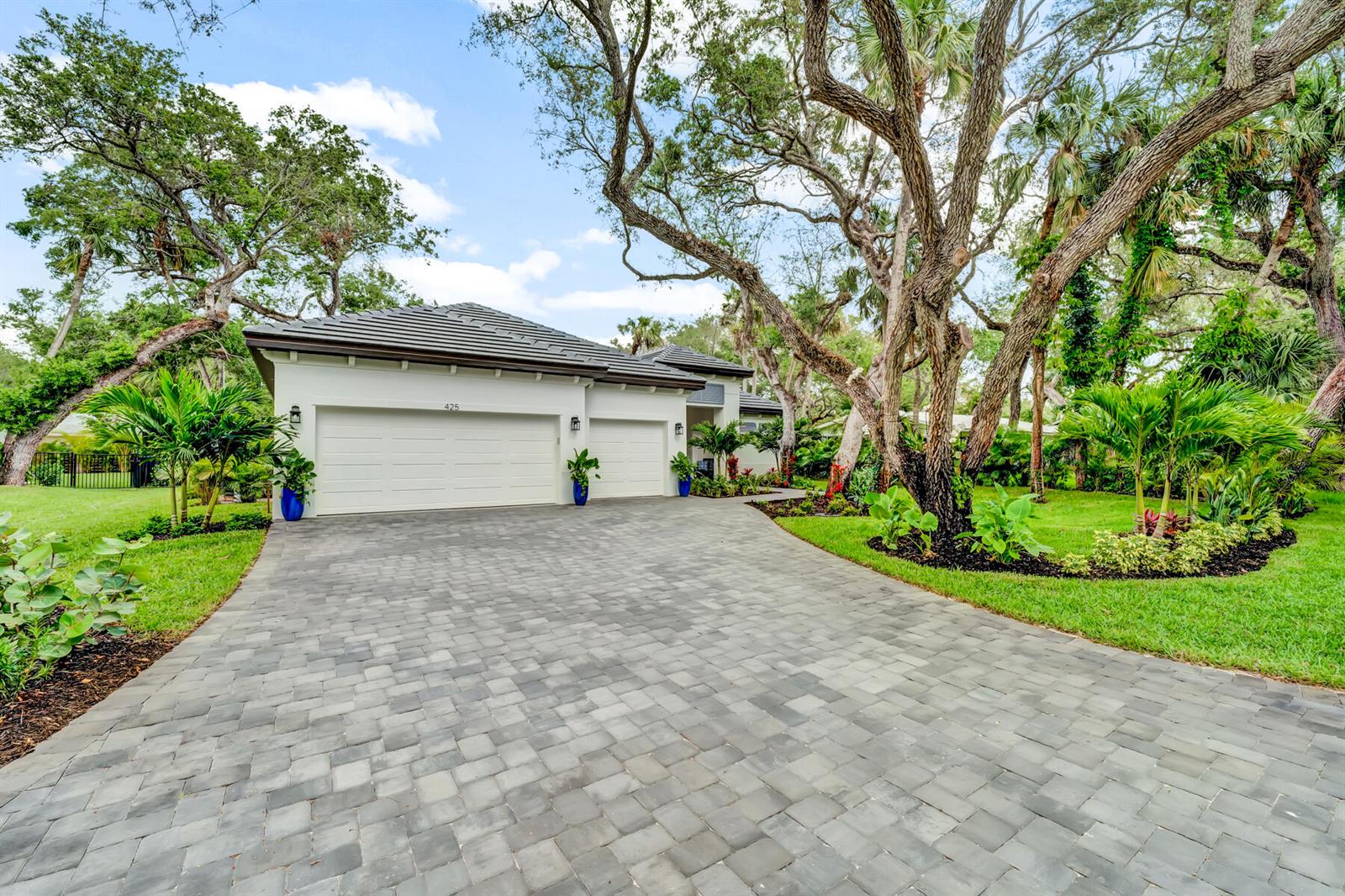 A white house with a gray tiled roof and a paved driveway surrounded by trees — VERO BEACH, FL