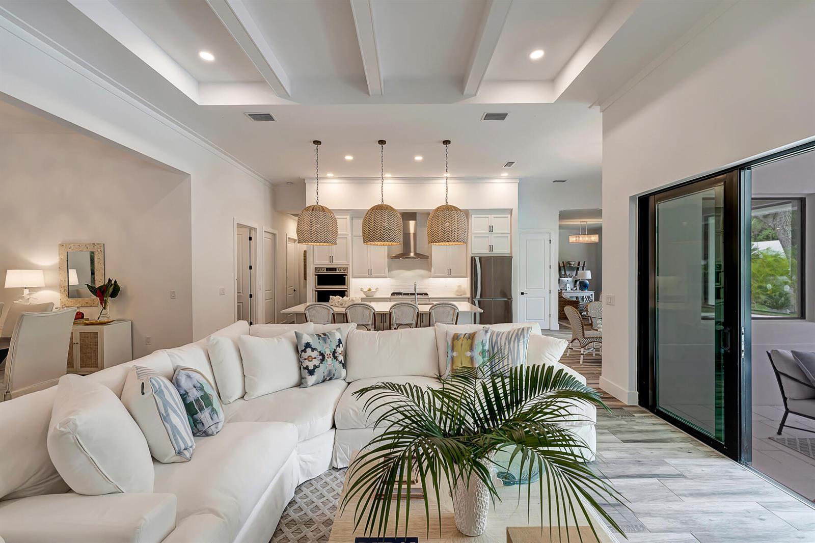 A white sectional sofa faces an open-concept kitchen with a large island and pendant lights — VERO BEACH, FL