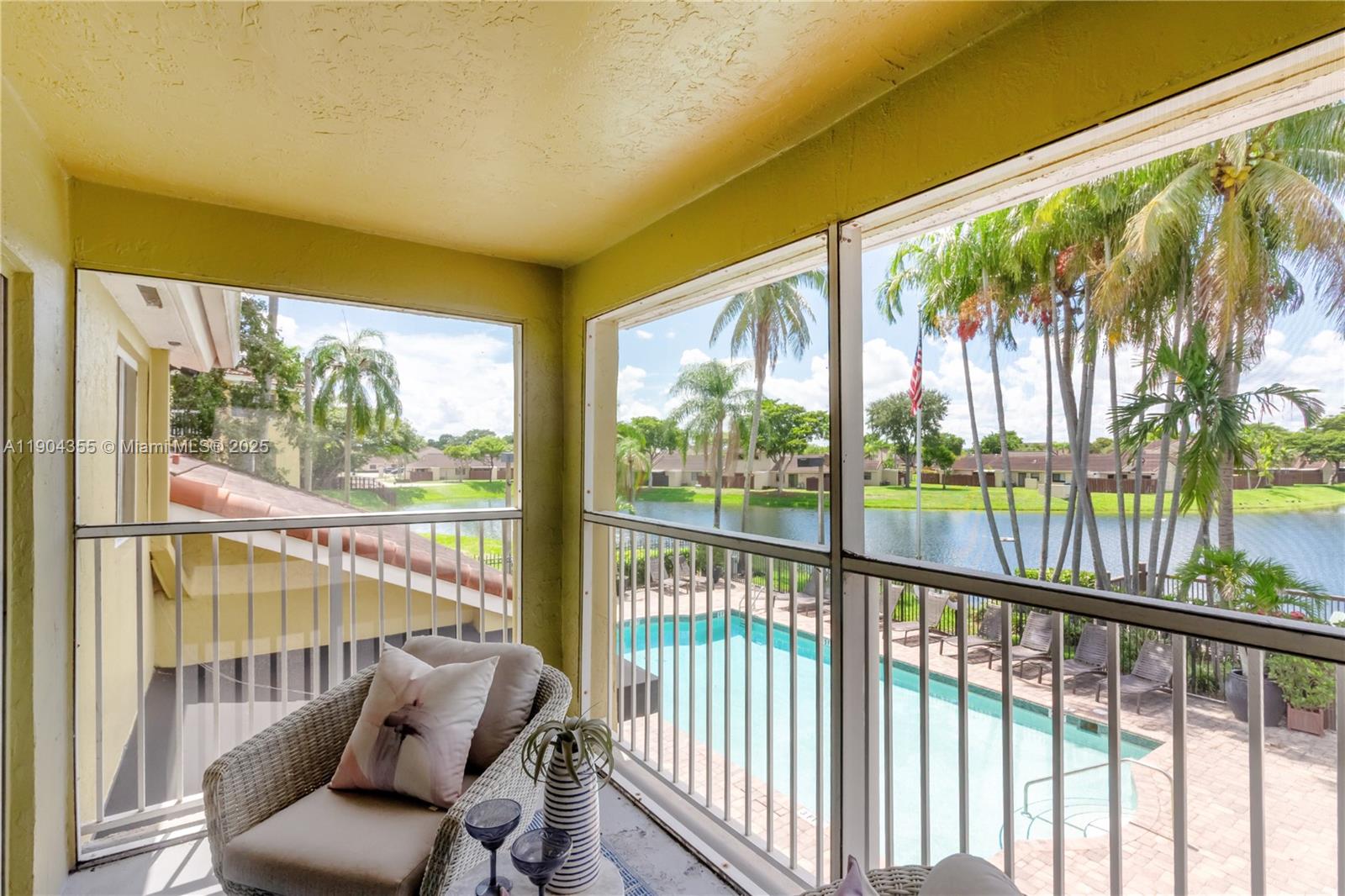 A screened-in balcony overlooks a swimming pool and a lake with palm trees — 17230 NW 64th Ave, Miami Lakes FL 33015, MIAMI LAKES, FL