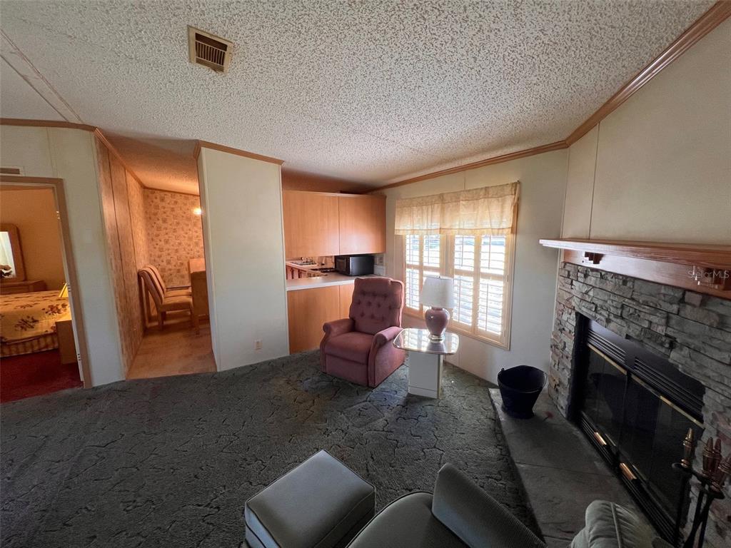 A living room features a stone fireplace, a recliner, and a view into a dining area — 10070 S ARABIAN AVENUE, FLORAL CITY, FL