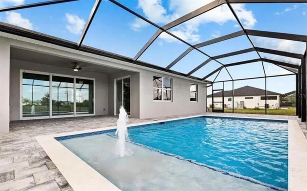 A screened-in patio features a swimming pool with a fountain and a paved deck — 928 NE 3RD AVENUE, CAPE CORAL, FL